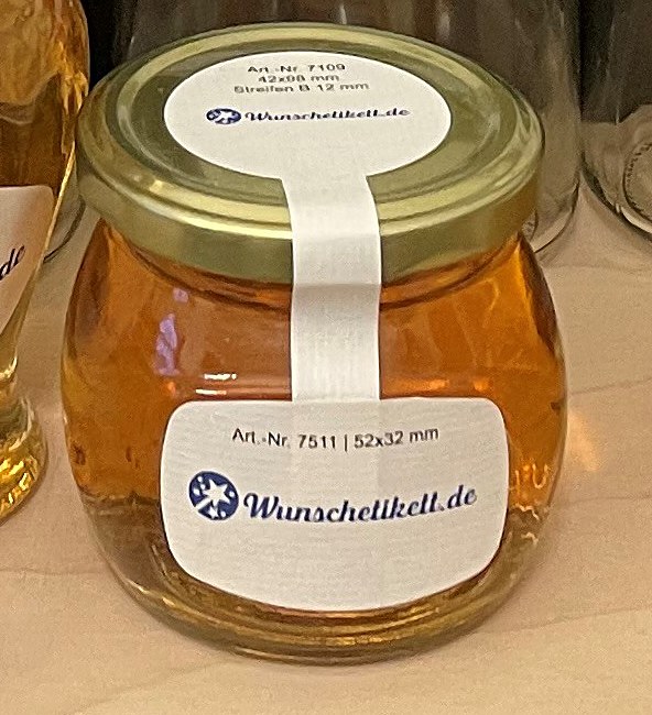 Honigglas mit Etikett von Wunschetikett.de und einem Gewährverschluss-Streifen über dem Deckel
